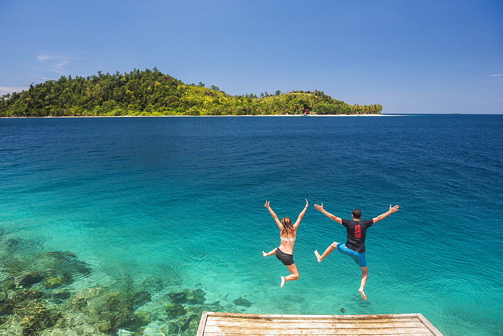 Couple jumping into the Pacific Ocean at Twin Beach, a tropical white sandy beach near Padang in West Sumatra, Indonesia, Southeast Asia, Asia