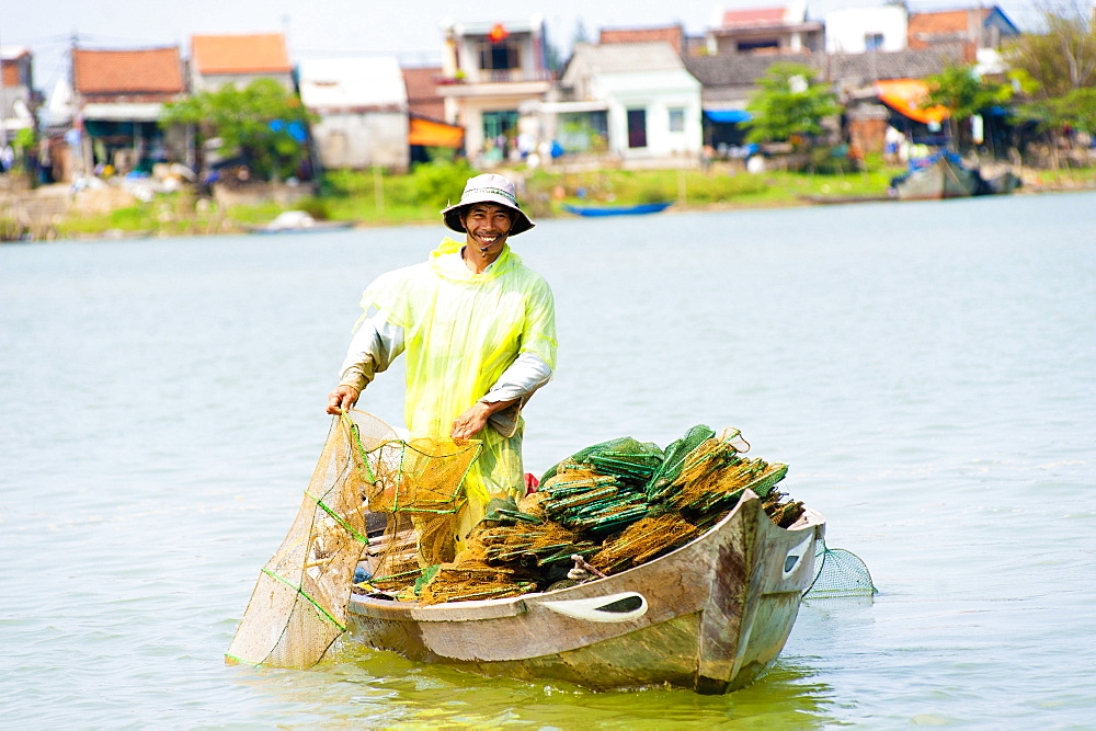 Man fishing from his boat at the old port town of Hoi An, Vietnam, Indochina, Southeast Asia, Asia