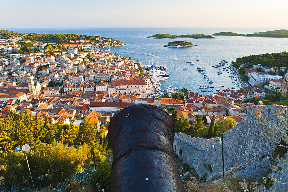 Hvar Fortress cannon and Hvar Town at sunset taken from the Spanish Fort (Fortica), Hvar Island, Dalmatian Coast, Adriatic, Croatia, Europe 