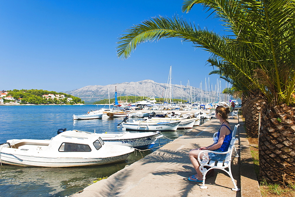 Tourist sitting in Lumbarda Harbor, Korcula Island, Dalmatian Coast, Adriatic, Croatia, Europe