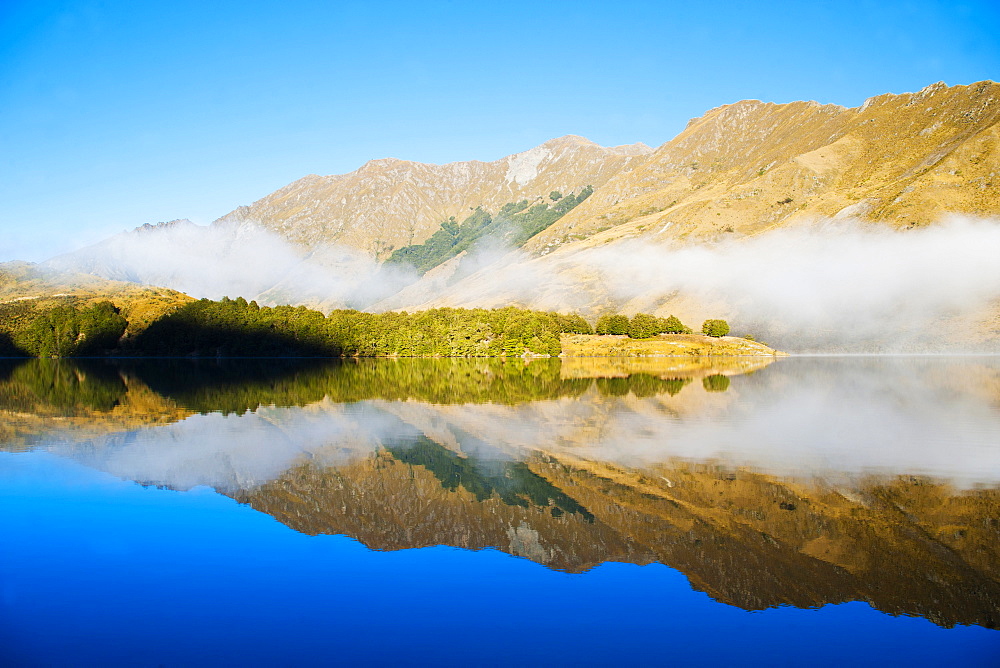 Misty dawn reflections on calm Lake Moke, Queenstown, Otago, South Island, New Zealand, Pacific