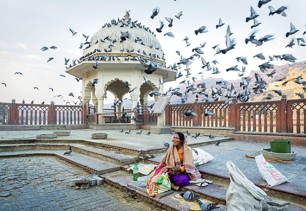 Woman feeding pigeons with corn at Amber Fort in Rajasthan, India, Asia