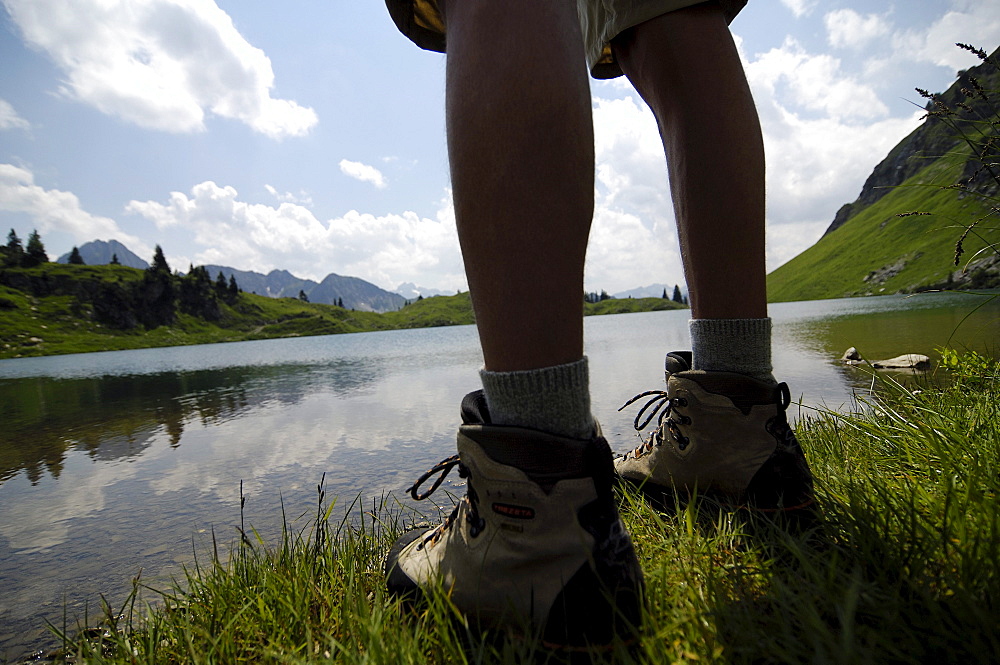 View at the legs of a hiker in front of a mountain lake, Allgaeu Alps, Bavaria, Germany, Europe