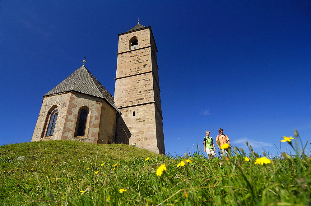 Hikers standing beside a church under blue sky, South Tyrol, Italy, Europe