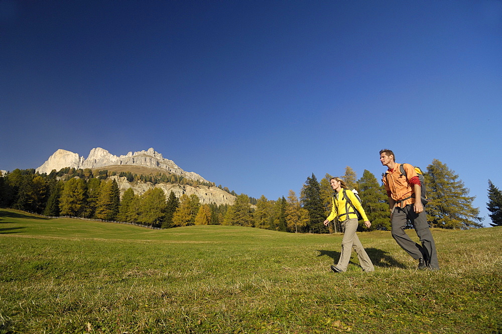 Young couple hiking under blue sky, Rosengarten, Dolomites, South Tyrol, Italy, Europe