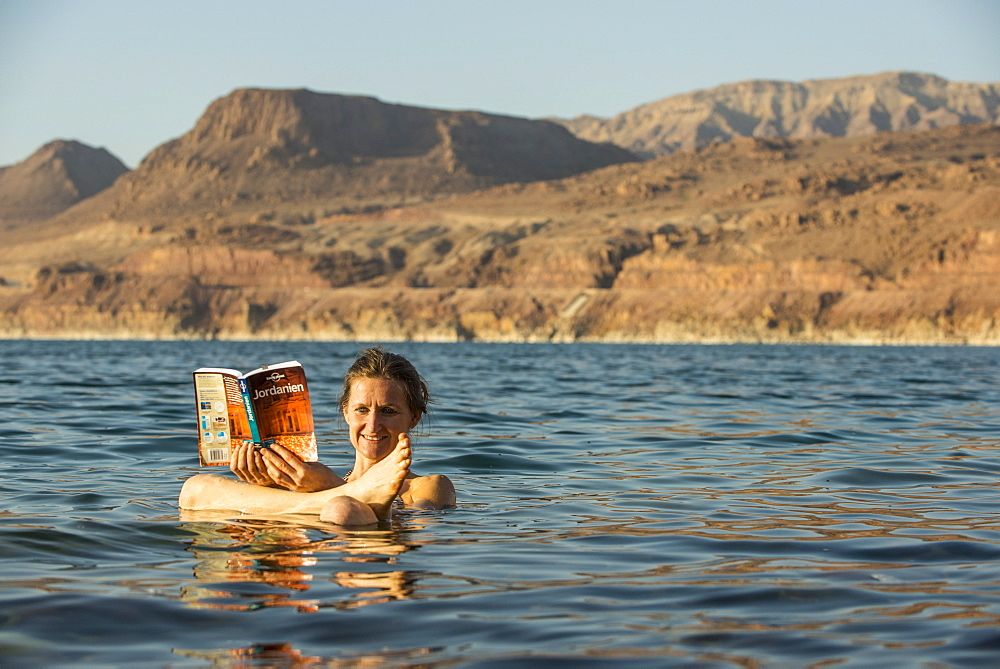 Woman reading a guidebook in Dead Sea, Jordan, Middle East