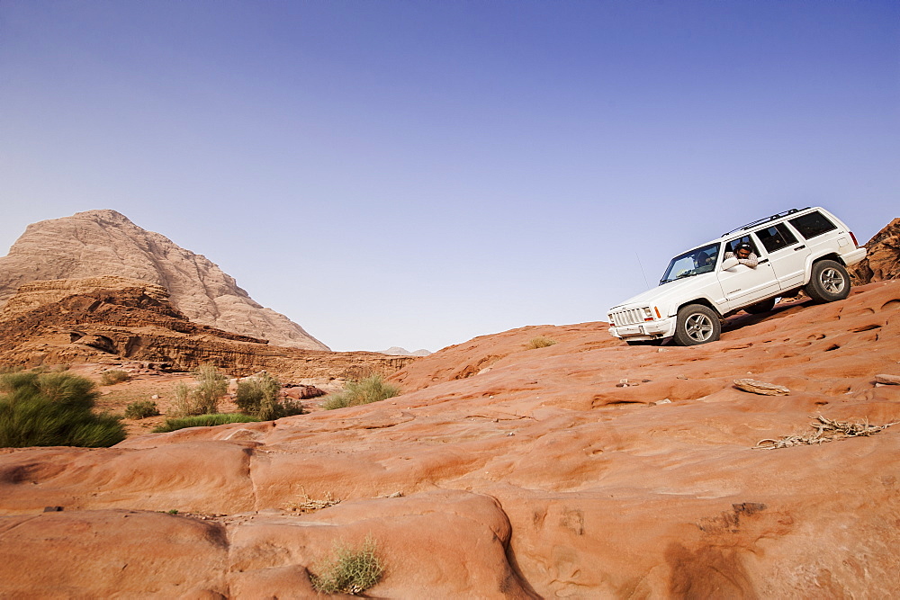 Off-road vehicle downhill driving above a slab of rock, Wadi Rum, Jordan, Middle East