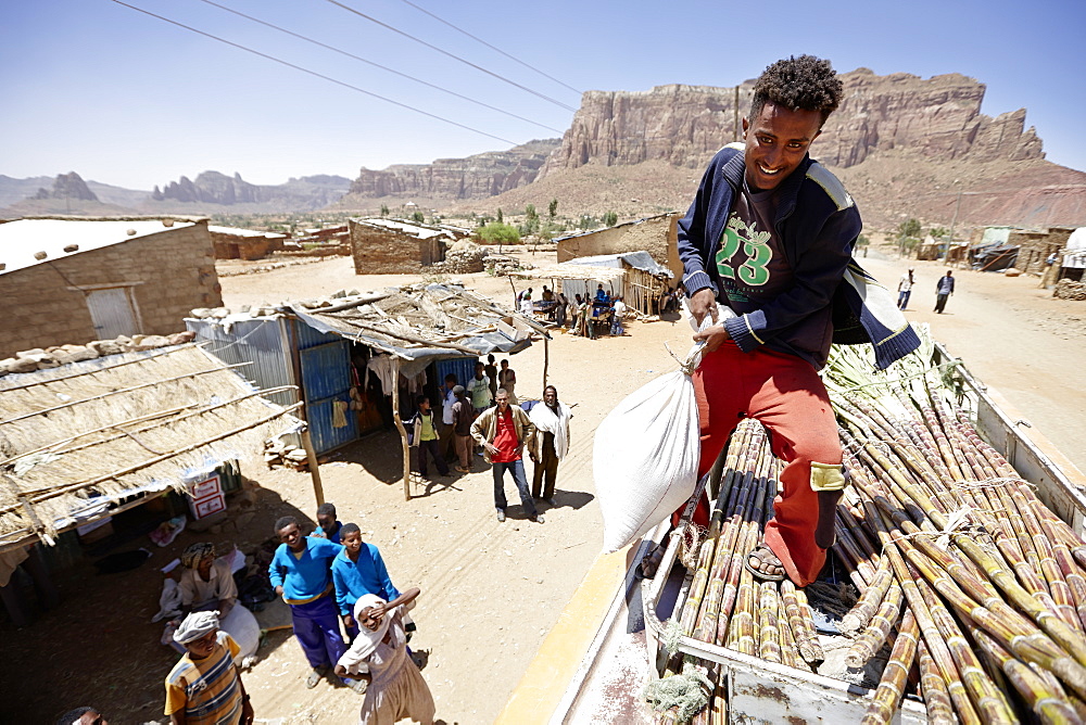 Loading of sugar cane and bags of grain on the roof of a cross-country coach, Gheralta mountains in background, Magab, Tigray region, Ethiopia