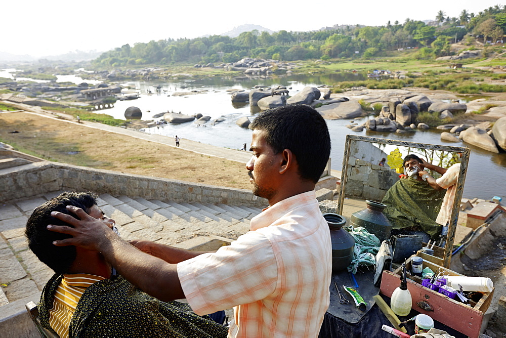 Hairdresser working above the Tungabhadra River, Hampi, Karnataka, India