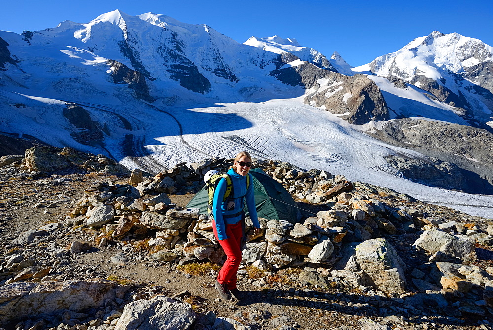 Woman hiking with view to Piz Palue (3905 m), Bellavista (3922 m), Piz Bernina (4049 m) and Pers glacier, Engadin, Grisons, Swit