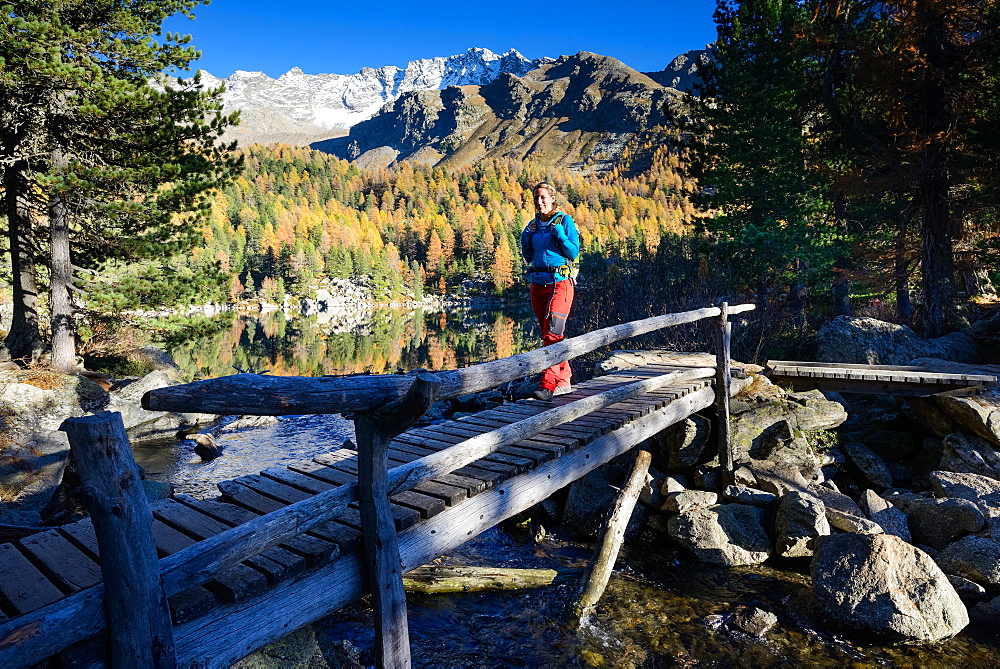 Woman hiking along the shore of lake Saoseo (2028 m) with Scima di Saoseo (3264 m), Valposchiavo, Grisons, Switzerland