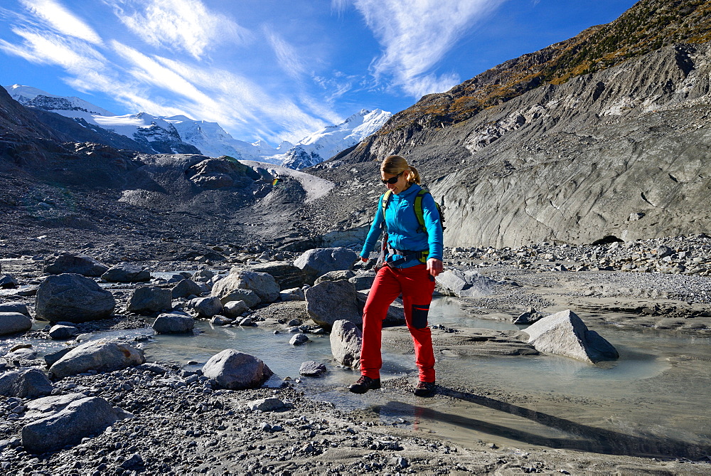 Woman crossing the Morteratsch Creek near the glacier mouth of Morteratsch glacier with view to Bellavista (3922 m), Piz Bernina