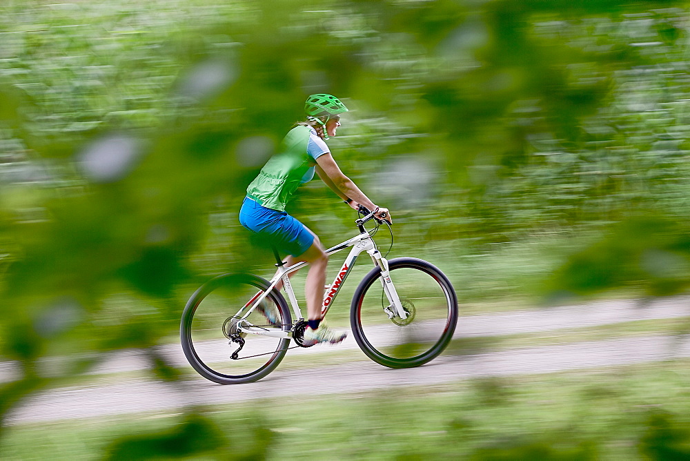 Woman bicycling, Chiemgau, Bavaria, Germany