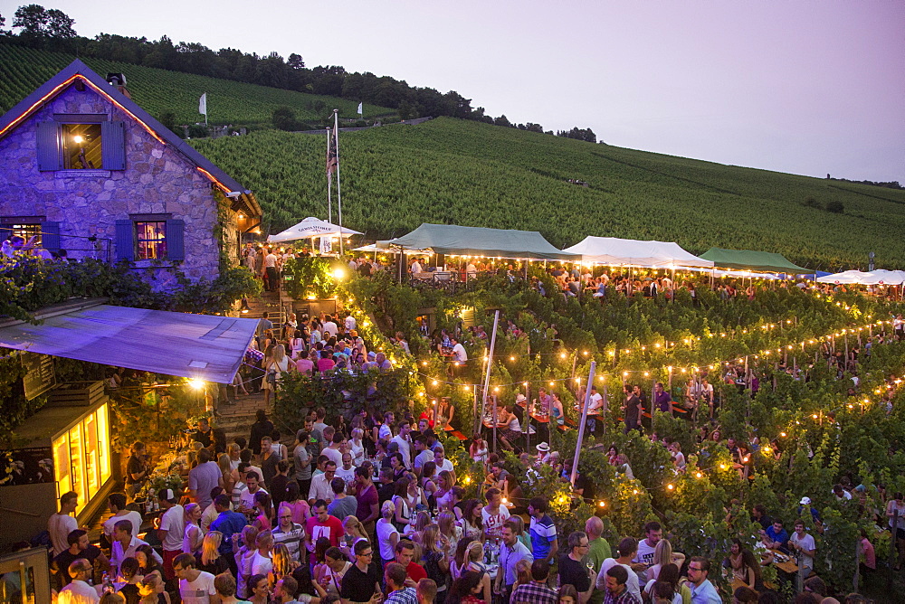 People at Hoffest celebration at Weingut am Stein winery at dusk, Wuerzburg, Franconia, Bavaria, Germany