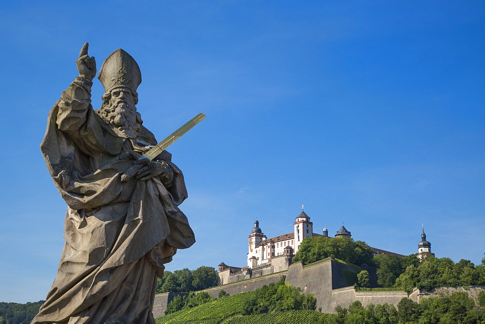 Statue on Alte Mainbruecke bridge across the Main river with Marienberg fortress on the hillside, Wuerzburg, Franconia, Bavaria,