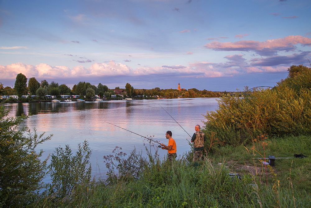 Two fishermen on the banks of the Main river with camp site at sunset, Volkach, Franconia, Bavaria, Germany