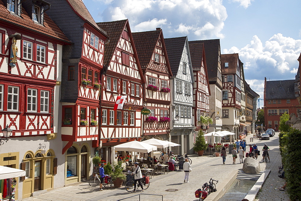 Half-timbered house in the old town with people sitting outside cafes and restaurants, Ochsenfurt, Franconia, Bavaria, Germany