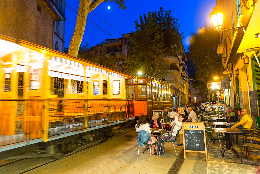 historical tram driving between Port de Soller and Palma de Mallorca in the evening, guests in restaurants, Serra de Tramuntana, Soller, Majorca, Balearic Islands, Spain, Europe