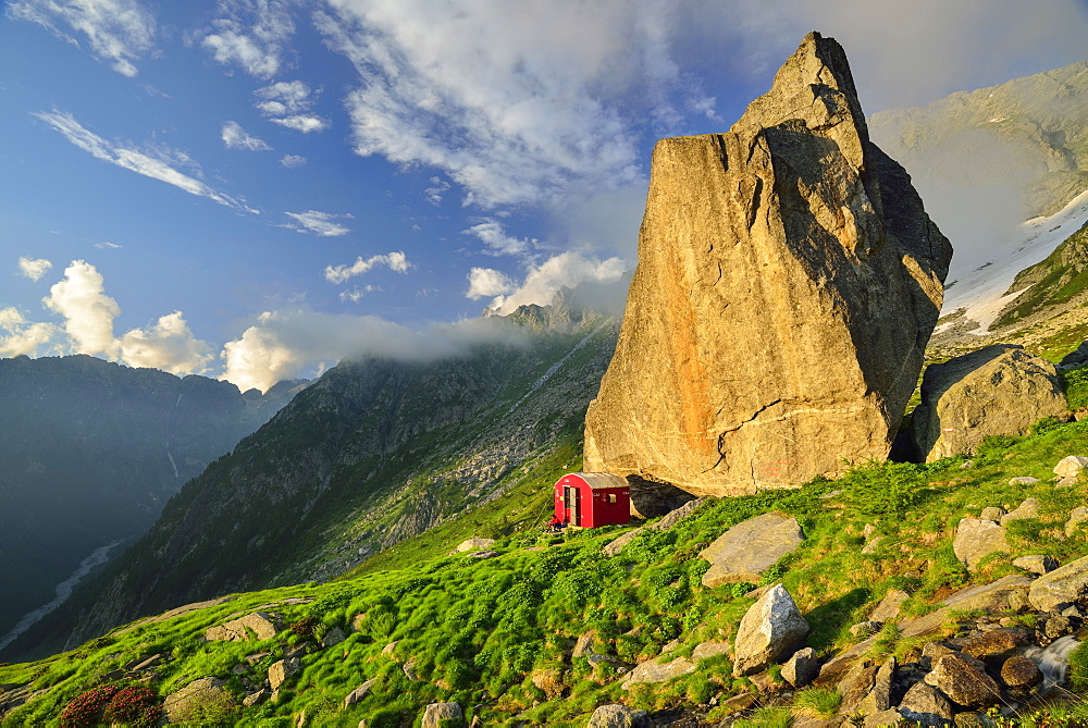 Red bivouac beneath boulder, Lombardy, Italy