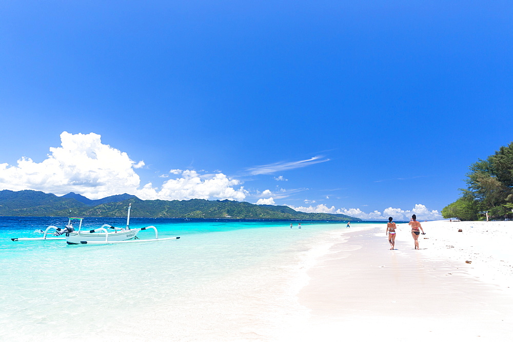 Two women walking along white sandy beach, Gili Meno, Lombok, Indonesia