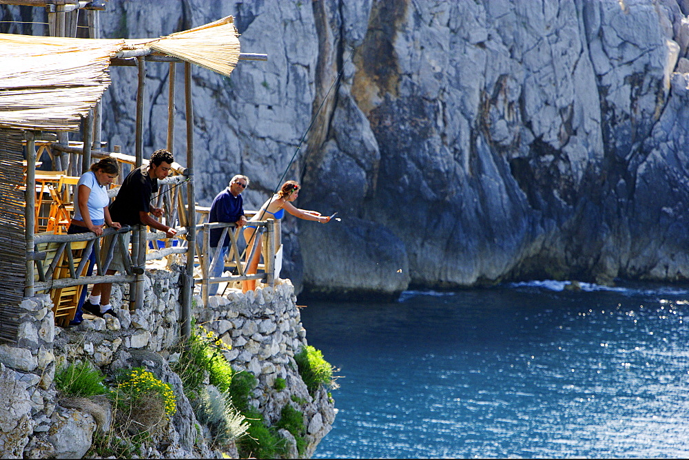 People fishing at the rocky coast in the sunlight, Capri, Italy, Europe
