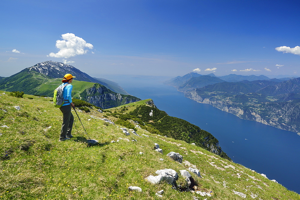 Female hiker looking over Monte Baldo and lake Garda, Monte Altissimo, Garda Mountains, Trentino, Italy