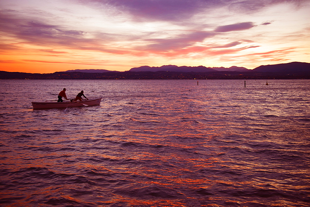 Fishing boat at sunset, Sirmione with view to Desenzano del Garda, Lombardy, Italy, Europe