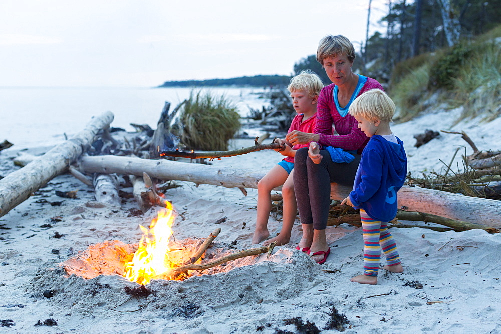 Familiy, mother and two children sitting around a campfire, adventure, dream beach between Strandmarken und Dueodde, sandy beach, summer, Baltic sea, Bornholm, Strandmarken, Denmark, Europe, MR