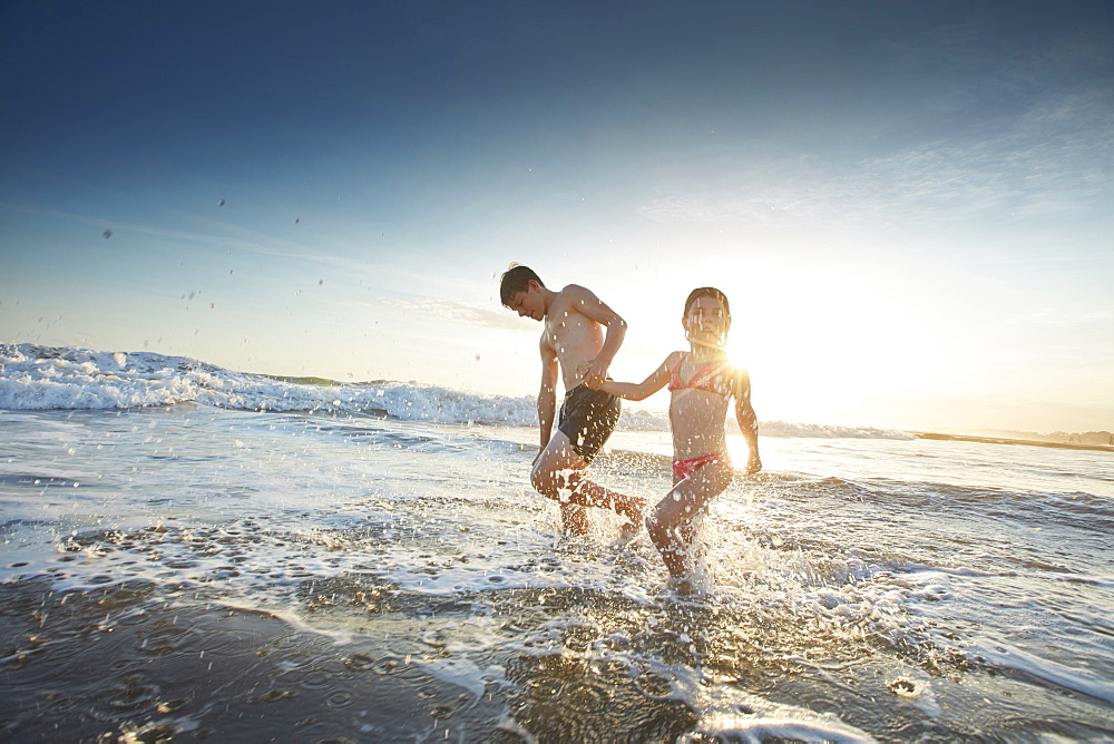 Sibling children on the beach of Canggu, low tide, Bali, Indonesia