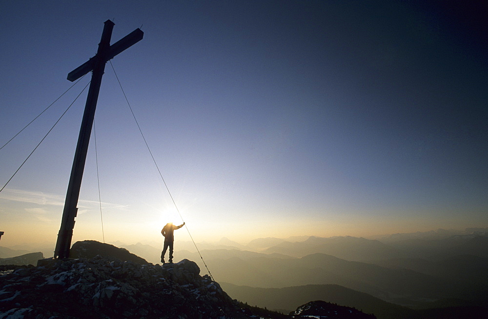 Hicker in front of summit cross of the Benediktenwand, Bavarian foothills of the Alps, Upper Bavaria, Bavaria, Germany