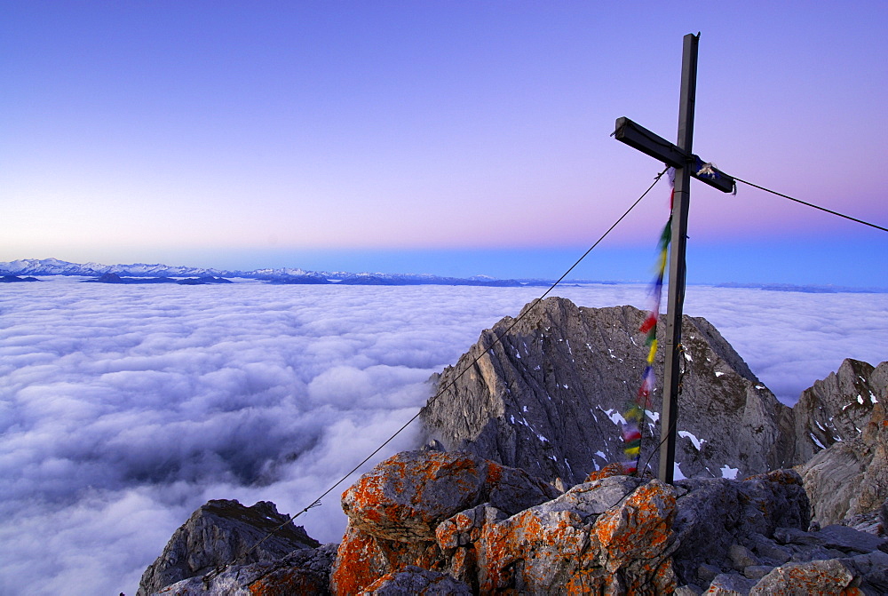 Summit cross with prayer flags on mountain Ellmauer Halt, Kaiser range, Tyrol, Austria