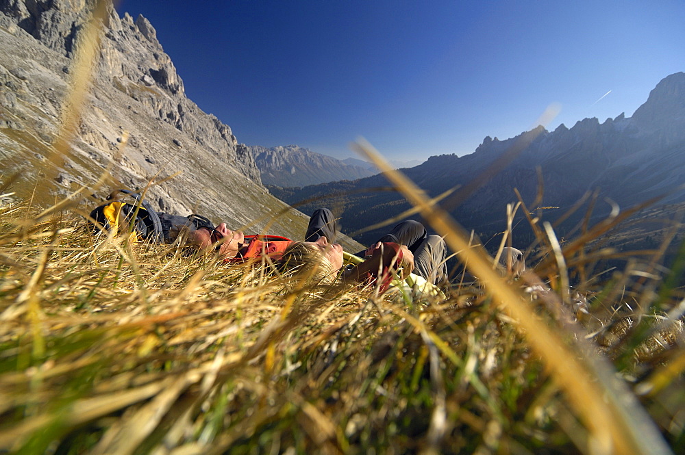 Couple resting on mountain meadow, Val di Fassa, Dolomites, Trentino-Alto Adige/Südtirol, Italy