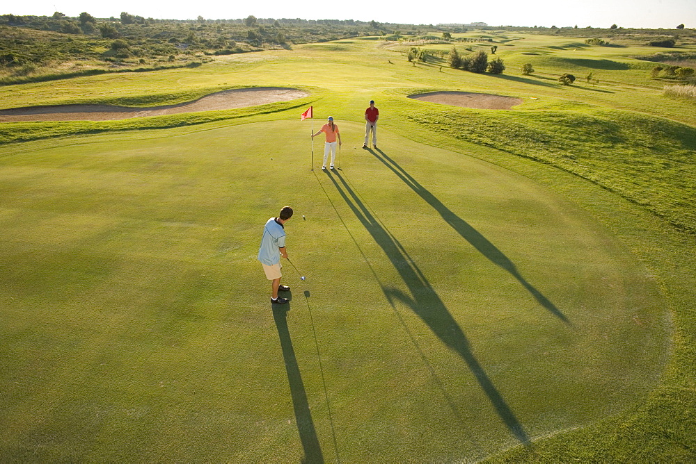 Golfers on golf course, long shadows, Apulia, Italy