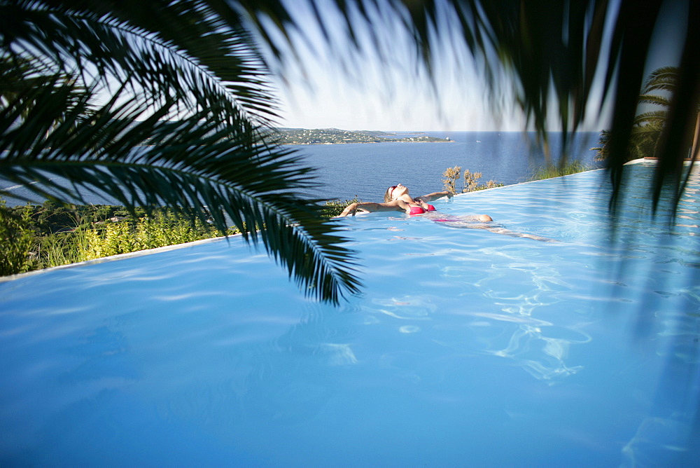 Woman in bikini leaning back in infinity pool, Porto Vecchio, Southern Corse