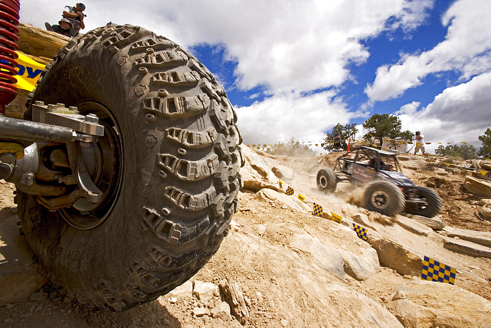 View of a racecar tyre in a Rock Crawling Race where a racing car is driving past in the backround, Rock Crawling, Moab, Utah, USA