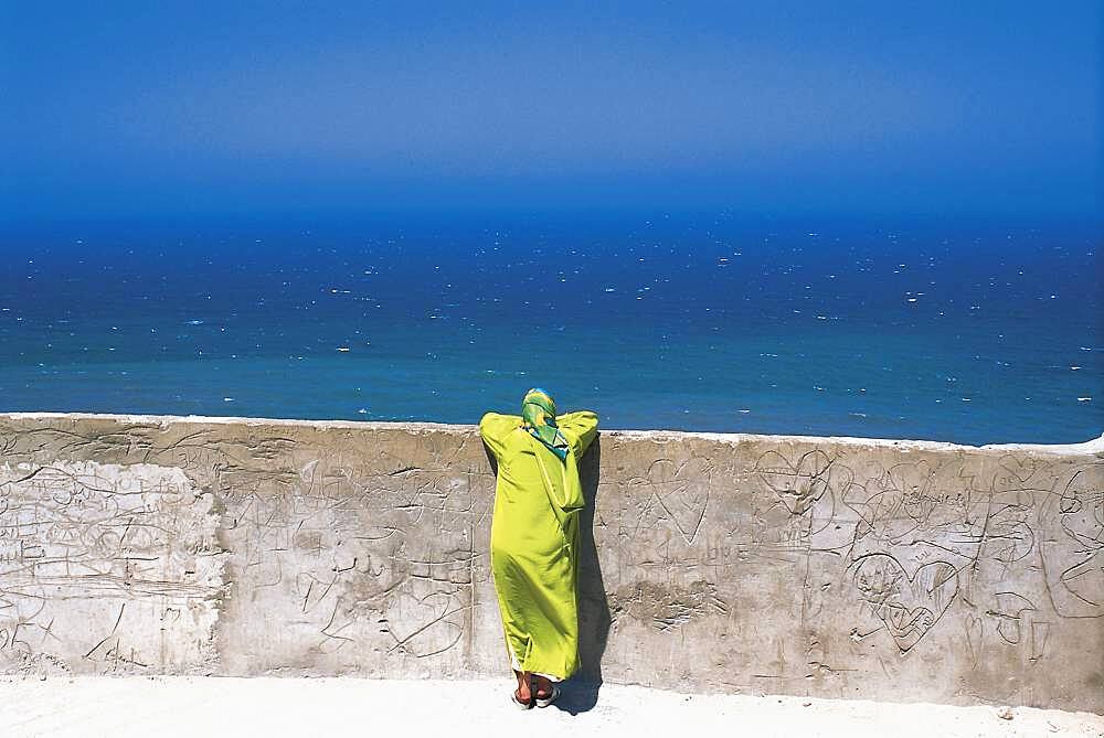 Woman leaning on a wall looking at the sea, Medina, Tanger, Morocco, Africa