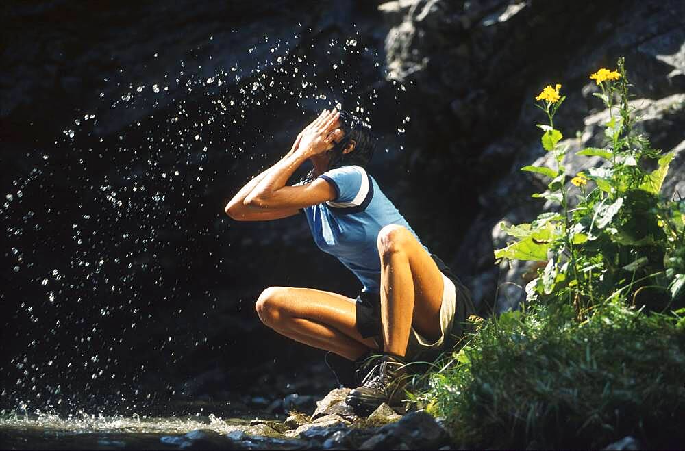 Young woman refreshing her face in a stream