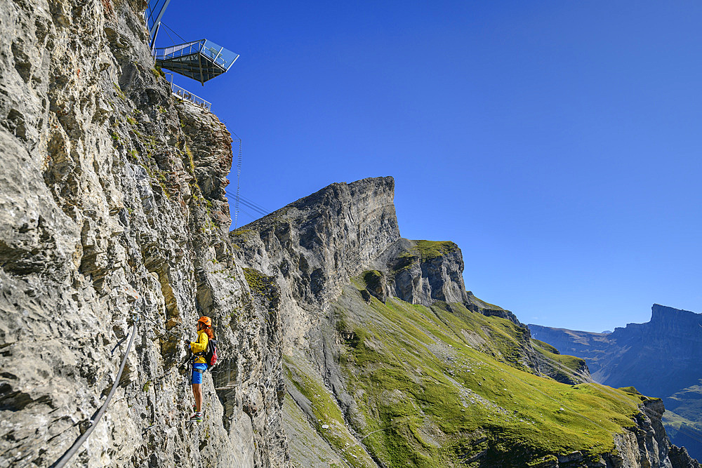 Woman climbs under the viewing platform on the Gemmi adventure via ferrata, Gemmi, Bernese Alps, Valais, Switzerland