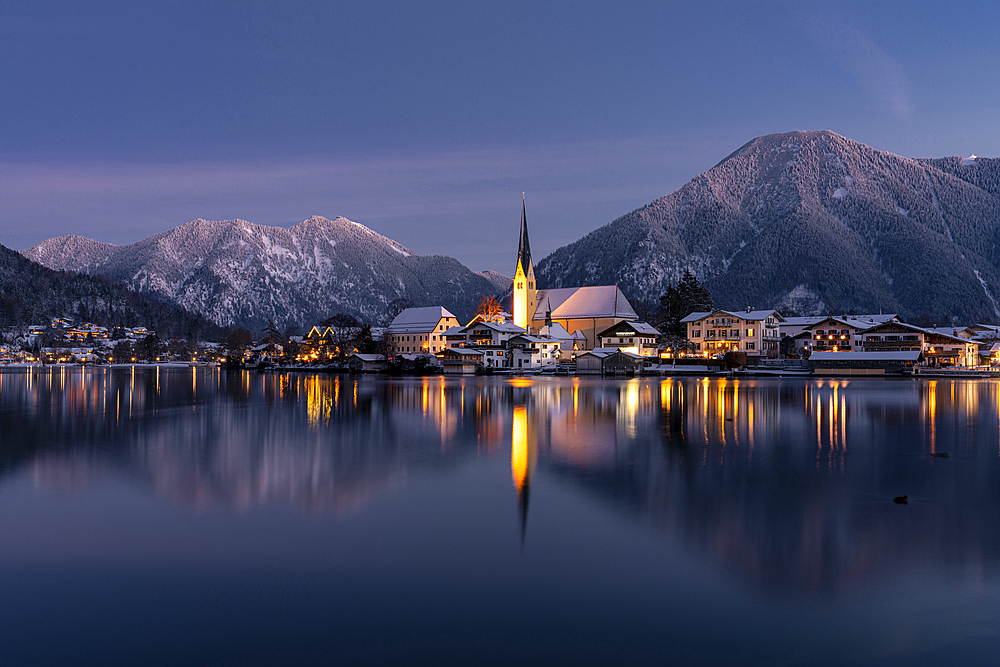 View over the wintry Tegernsee to the village of Rottach-Egern with the church Sankt Laurentius, Bavaria, Germany.