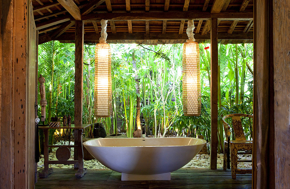 Freestanding bathtub inside an open bathroom in an old wooden house in Bali. Bali, Indonesia.