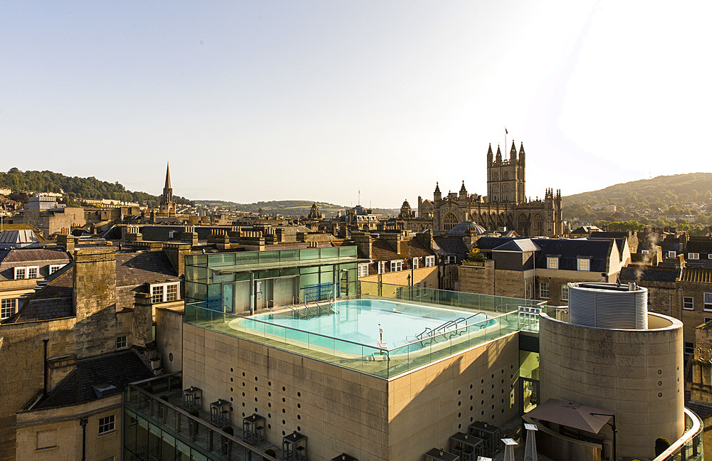 View of exterior roof-top pool set against the scenery of old turrets and buildgs, Horizontal. Bath. United Kingdom