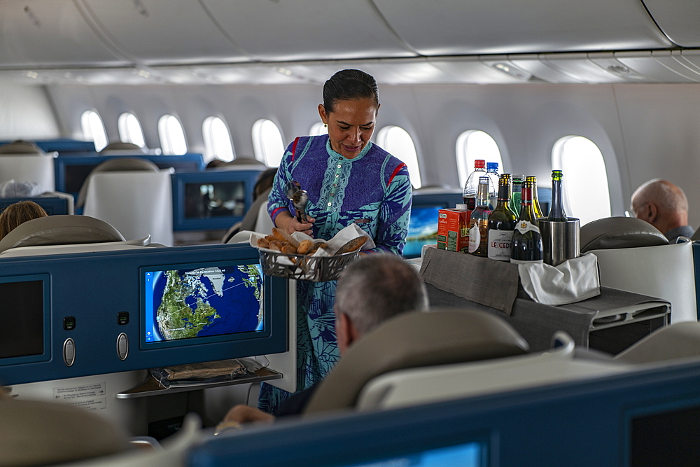 Flight attendant hands bread to passenger in Poerava Business Class aboard Air Tahiti Nui Boeing 787 Dreamliner aircraft on the flight from Paris Charles de Gaulle Airport (CDG) in France to Los Angeles International Airport (LAX) in the United States