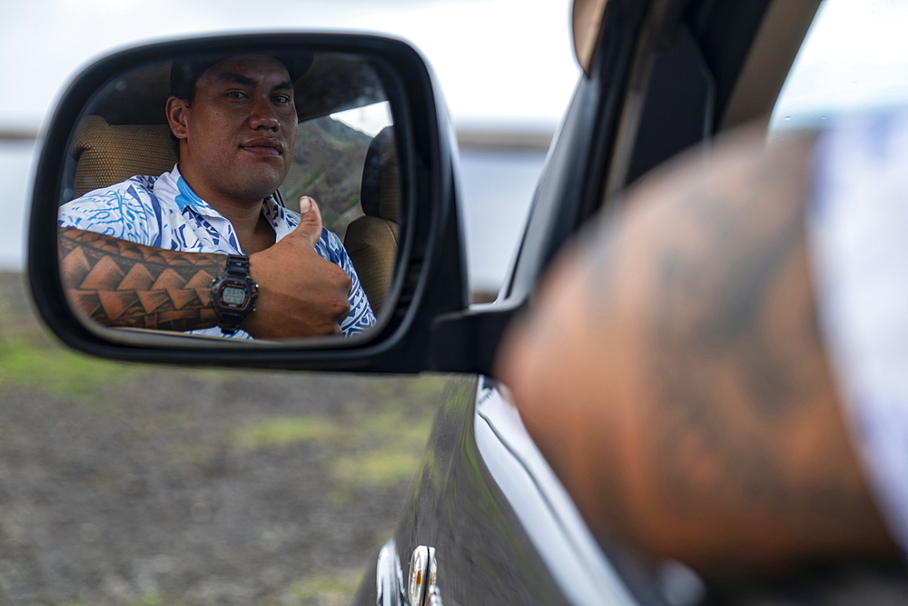 Thumbs up: a man with tattoos on his arm looks in the rearview mirror of his four-wheel drive vehicle, Tekoapa, Ua Huka, Marquesas Islands, French Polynesia, South Pacific