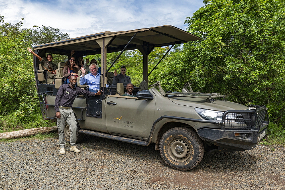 Group photo of happy visitors in safari vehicle operated by luxury resort tented Magashi Camp (Wilderness Safaris), Akagera National Park, Eastern Province, Rwanda, Africa