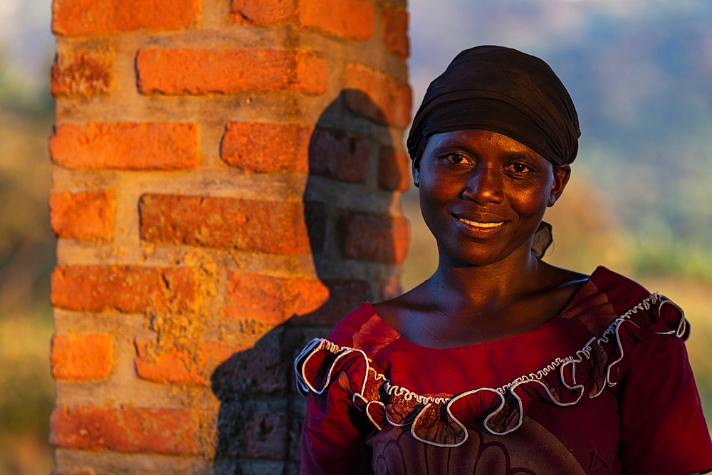 Portrait of a smiling Rwandan woman in late afternoon light, Kinunu, Western Province, Rwanda, Africa