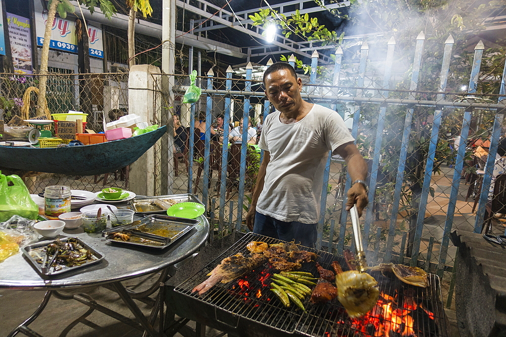 Man grills fresh fish, meat and vegetables at No Name BBQ in Ong Lang Village, Ong Lang, Phu Quoc Island, Kien Giang, Vietnam, Asia