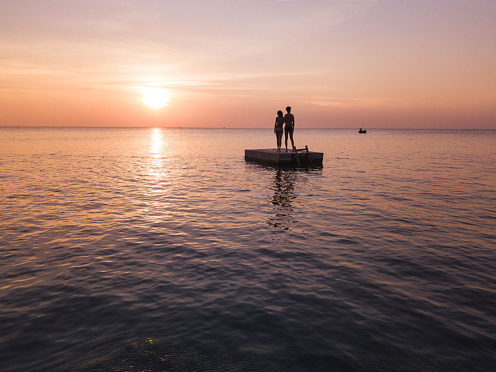 Aerial view silhouette of young couple standing on a bathing platform at sunset on Ong Lang Beach, Ong Lang, Phu Quoc Island, Kien Giang, Vietnam, Asia