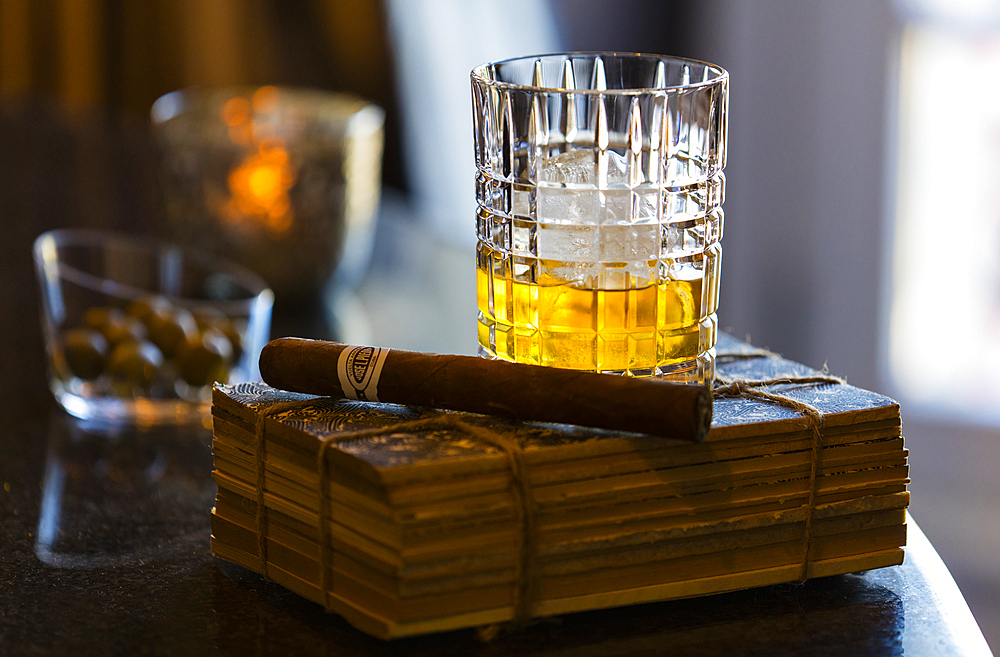 A stillife of a glass of whisky with a cigar set upon an old book. Shot in Algarve, Portugal.