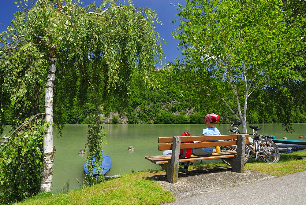 Woman sitting on bench near river Danube, Danube Cycle Route Passau to Vienna, Upper Austria, Austria