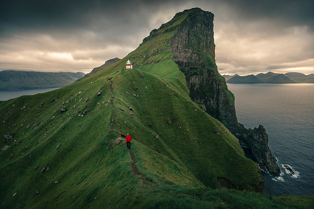 Man hikes to lighthouse on Kalsoy Island, Faroe Islands